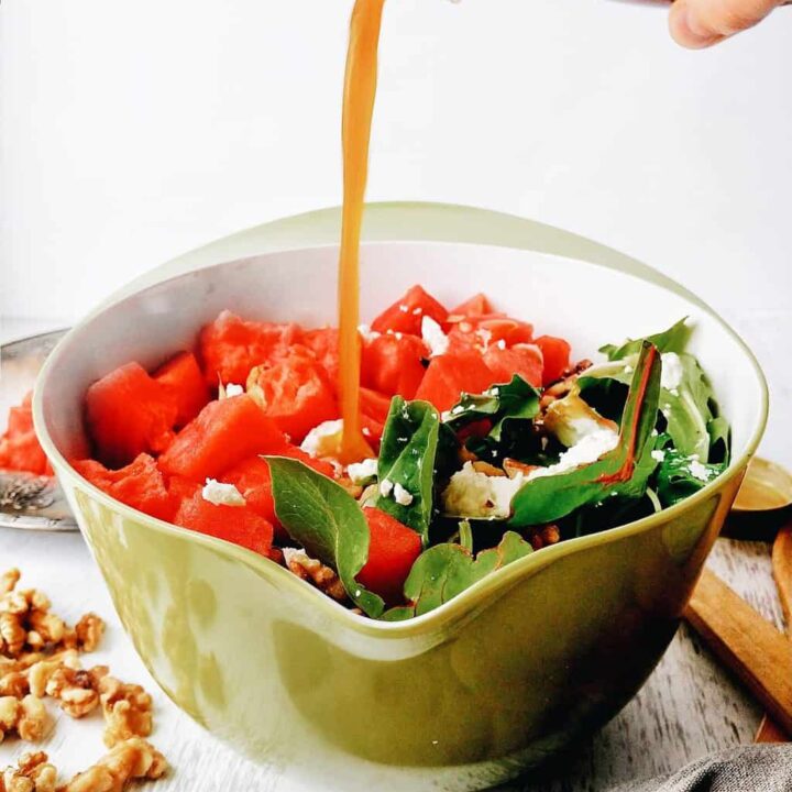 pouring red wine vinaigrette into a watermelon salad