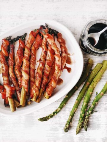 dish of bacon wrapped asparagus with balsamic glaze brushed over the top