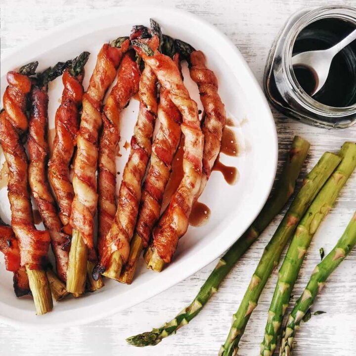 dish of bacon wrapped asparagus with balsamic glaze brushed over the top
