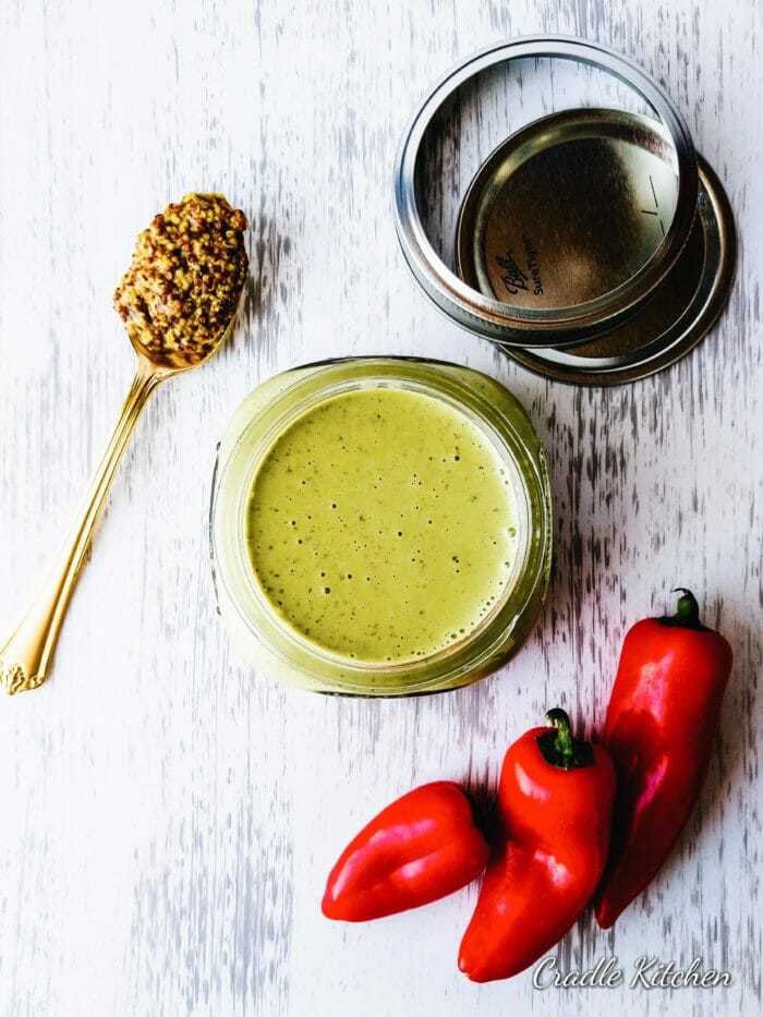 jar of cilantro sauce next to red peppers and whole grain mustard