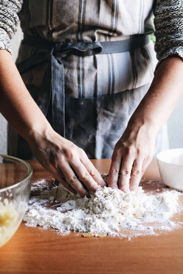 hands kneading dough on a table