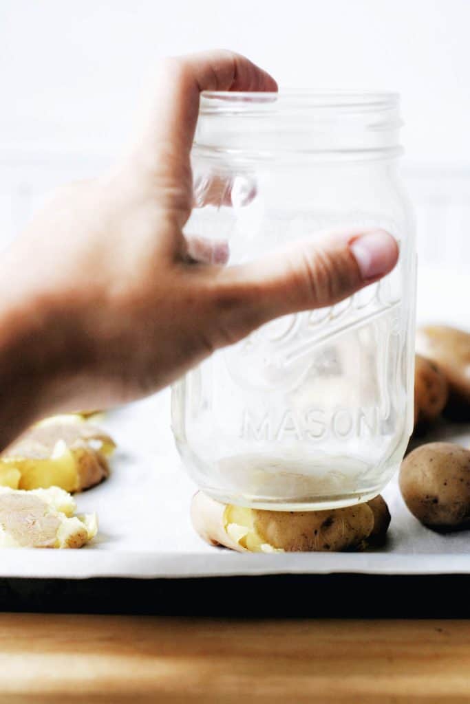 hand smashing a potato with a mason jar