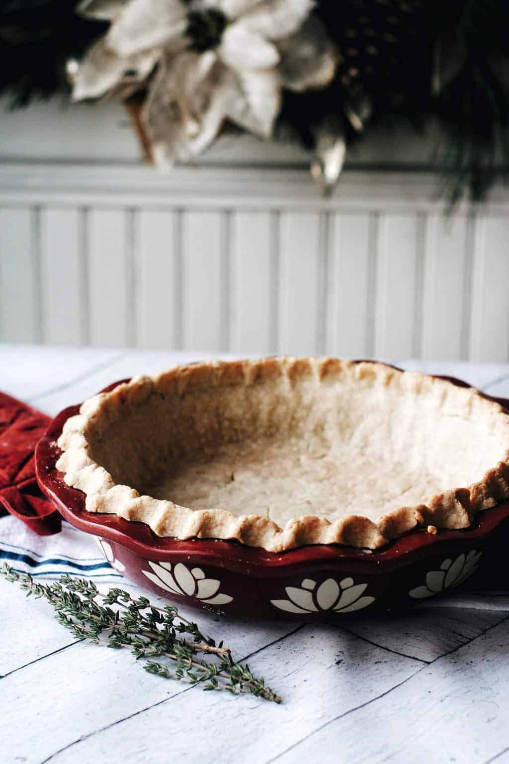 a flaky baked pie crust in a red holiday pie dish