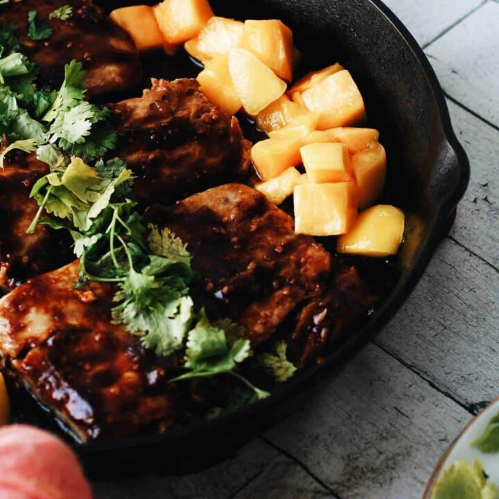 mahi mahi in a cast iron skillet with mango chunks and cilantro