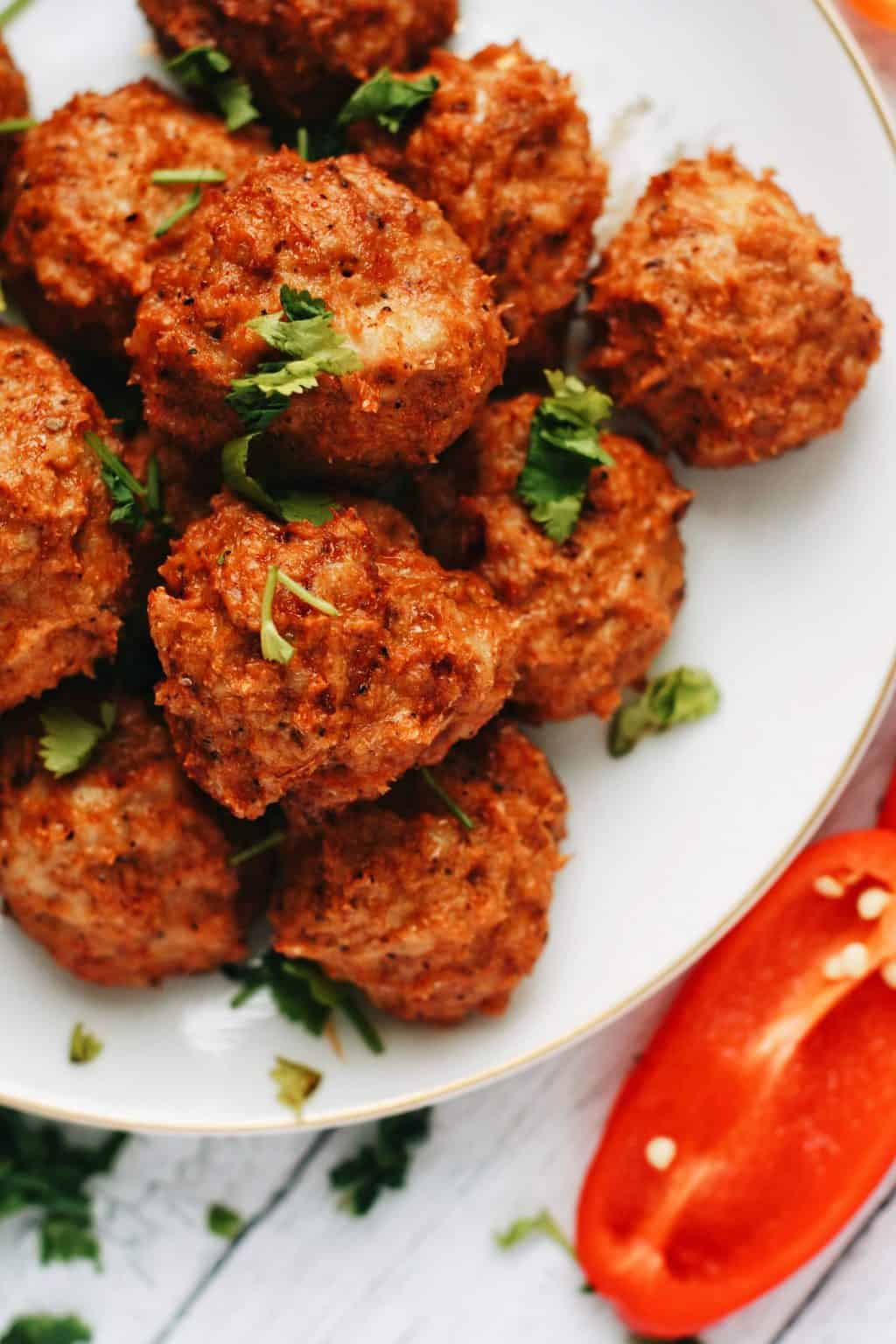 cajun chicken meatballs stacked together with peppers