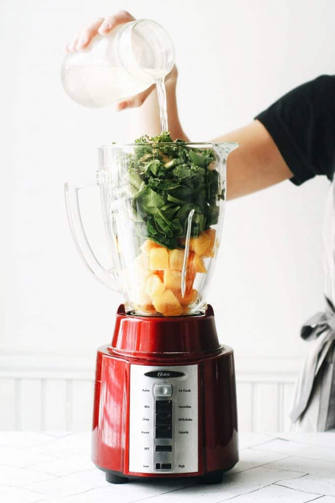 hand pouring aloe juice into a blender for a green smoothie recipe