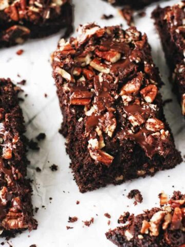 a thick almond flour brownie covered in melted chocolate chips and chopped pecans