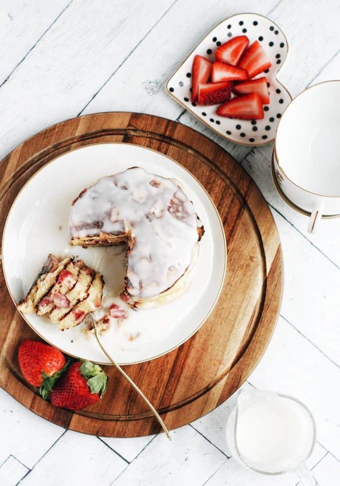 pancakes with icing and a bite taken out of them with strawberries