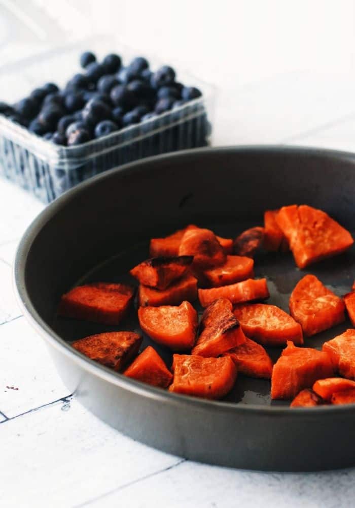 pan of roasted sweet potato and a carton of blueberries