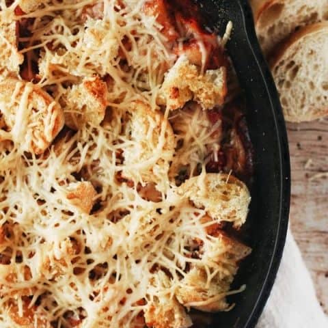 close up of a skillet filled with garlic bread and parmesan on baked gnocchi