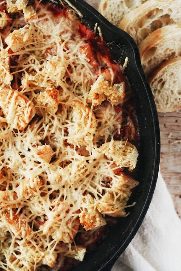 close up of a skillet filled with garlic bread and parmesan on baked gnocchi