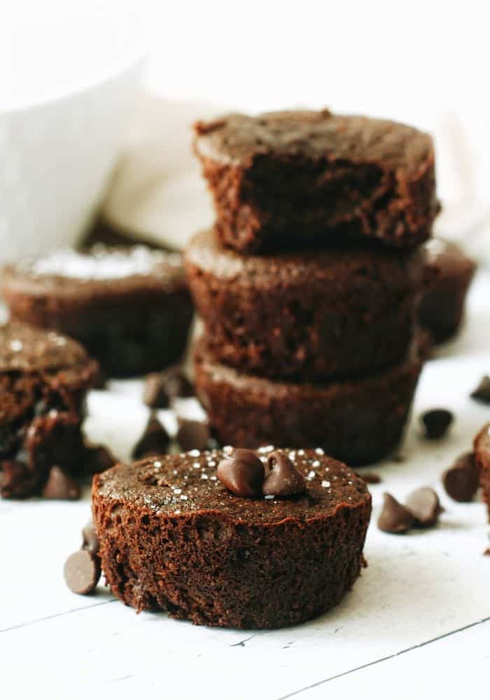 a double chocolate muffin with chocolate chips and sea salt in front of a stack of chocolate muffins