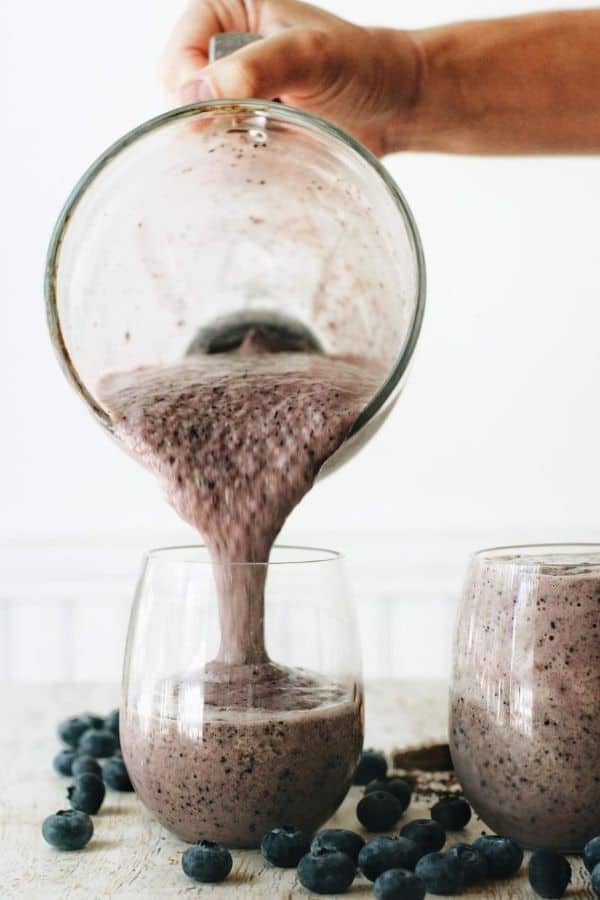 hand pouring blueberry coffee smoothie into cup