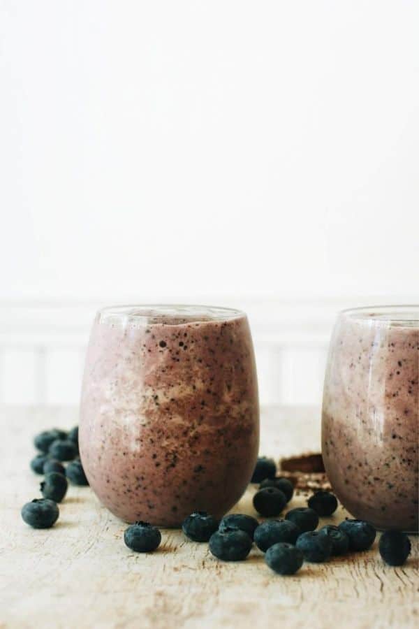 2 breakfast smoothies surrounded by blueberries