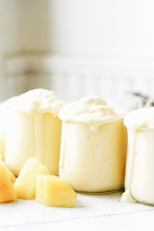 close up of creamy pineapple smoothies overflowing