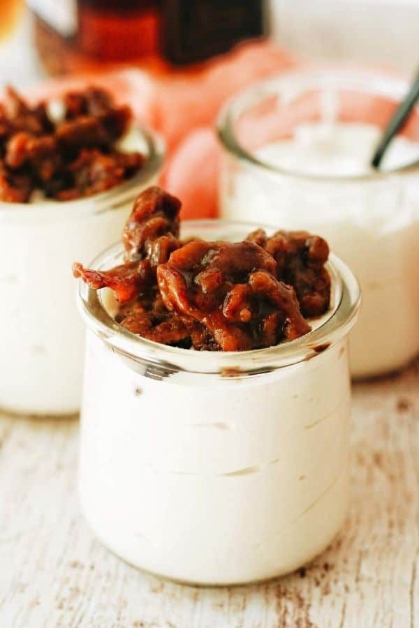 jars of no bake cheesecake with candied bacon on top