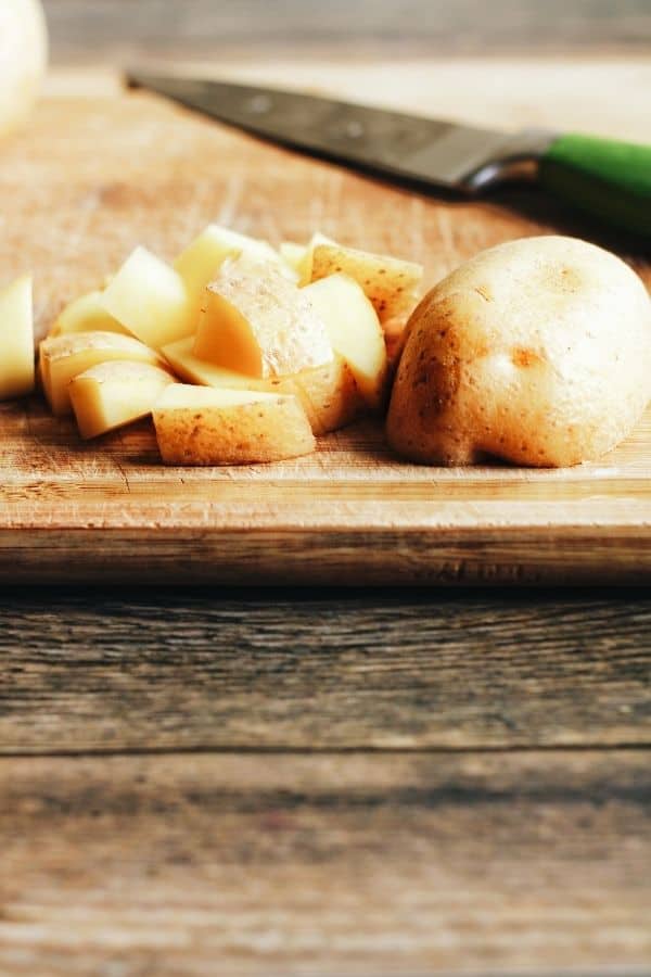 a golden potato cut into cubes on a rustic cutting board