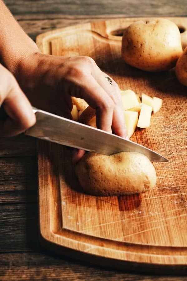 hands cutting golden potatoes on a cutting board