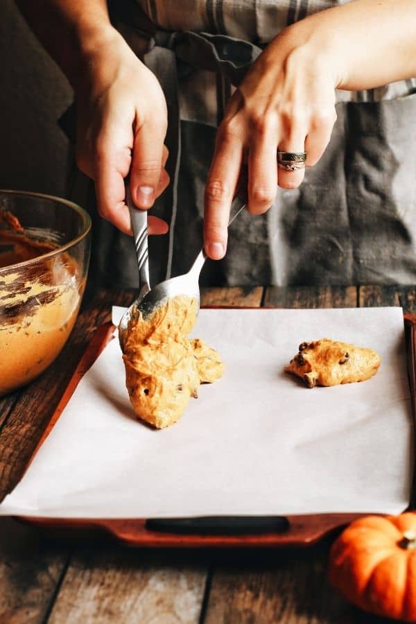 hands scooping cookie dough onto a tray 