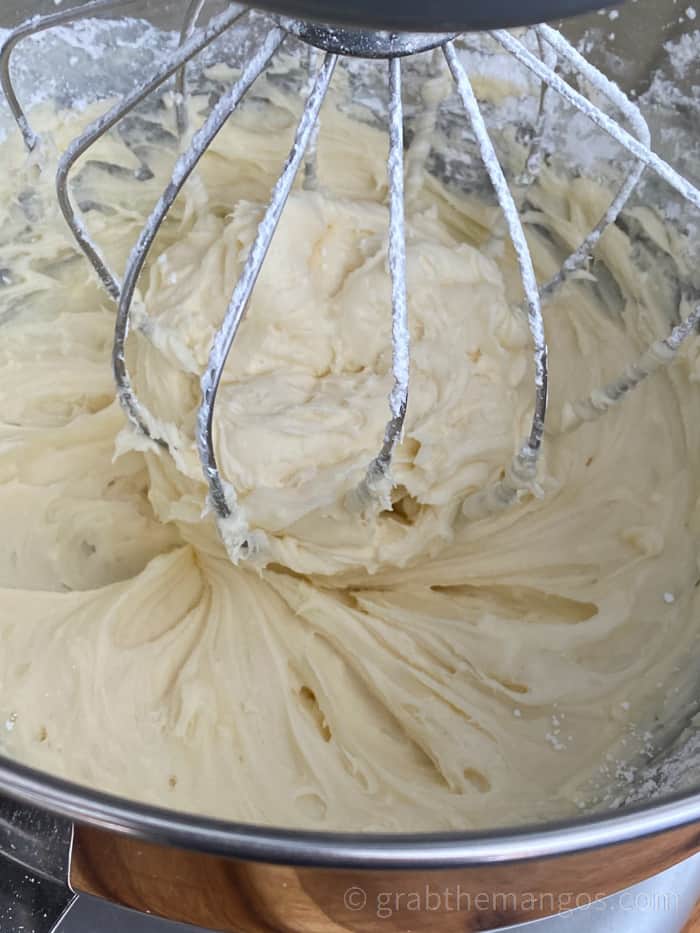 Cream cheese frosting in a metal mixing bowl with the mixer whisk 