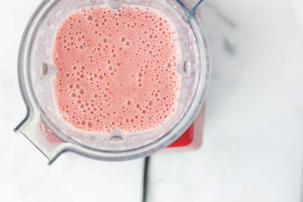 strawberry smoothie blended up in a blender 