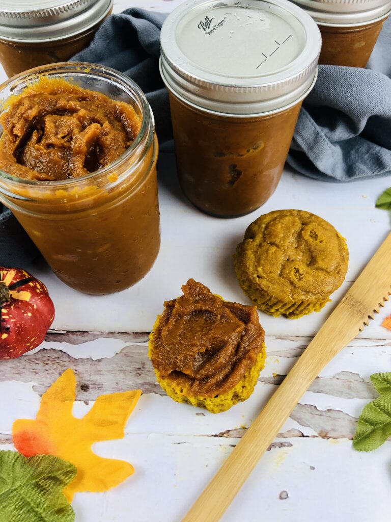 pumpkin butter in mason jars on a white table with muffins with pumpkin butter on top 