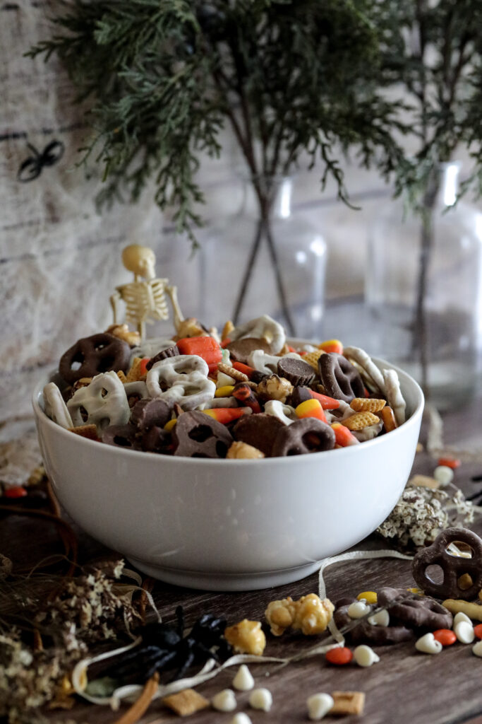 halloween trail mix in a white bowl with a Skelton in the background 