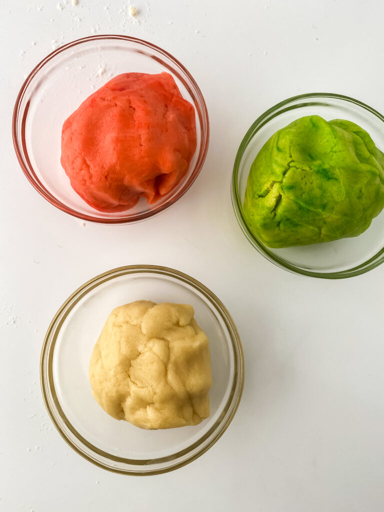 cookie dough balls in a glass bowl one is red one is green the other is plain dough 