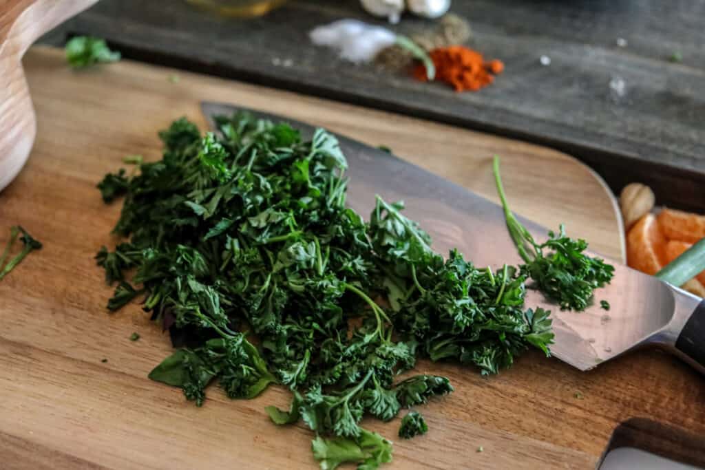 close up horizonal chopped parsley on a cutting board with a knife